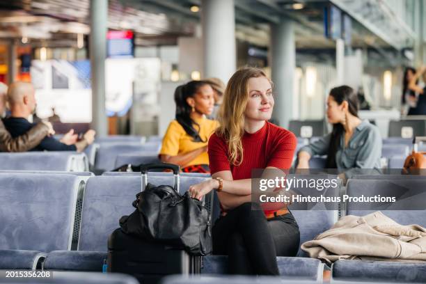 elegant woman gazes out window in airport lounge - woman blond looking left window stockfoto's en -beelden