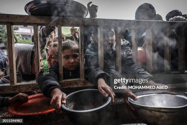 Displaced Palestinian children gather to receive food at a government school in Rafah in the southern Gaza Strip on February 19 amid the ongoing...