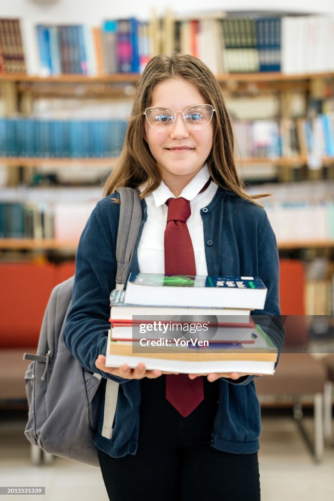 Porträt eines Mittelschülers mit Büchern in der Schulbibliothek
