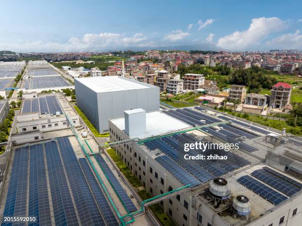 factories in towns with solar panels on their roofs - zona industriale foto e immagini stock