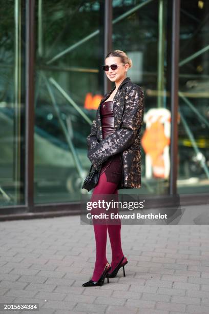 Guest wears sunglasses, a burgundy leather low-neck top, a bronze and black colored oversized blazer jacket, burgundy leggings, pointed shoes , a...