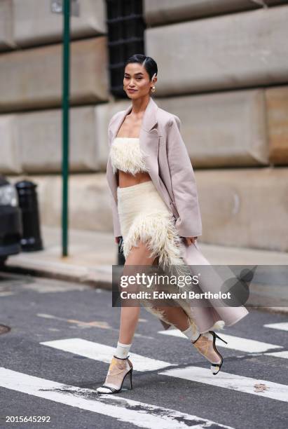 Guest wears hair pins, golden earrings, mauve lipstick, make-up , a long cotton coat, a beige fluffy crop top with fringes, a matching slit skirt ,...
