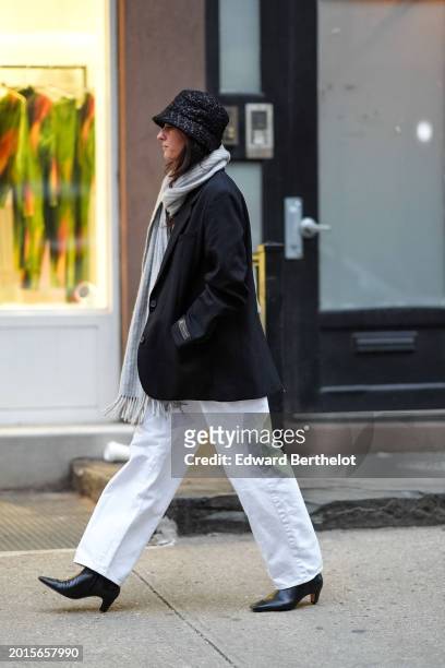 Guest wears a hat, a gray ribbed wool scarf with fringes, a black oversized blazer jacket , a belt, a white t-shirt, white wide-leg denim jeans pants...