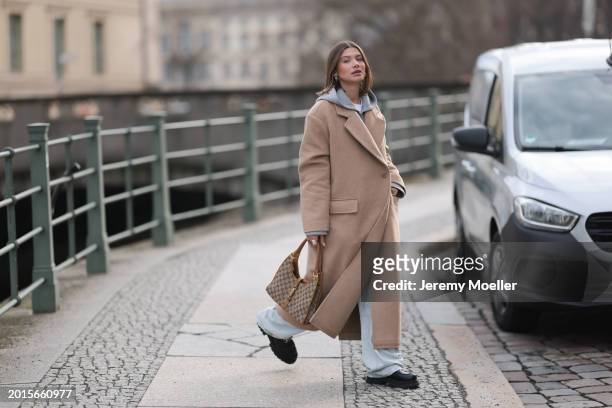 Sophia Geiss is seen wearing Arket light grey cotton hooded zip jacket, LeGer light blue wide leg denim / baggy jeans, LeGer beige oversized long...