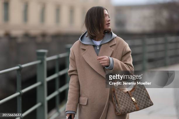 Sophia Geiss is seen wearing Arket light grey cotton hooded zip jacket, LeGer beige oversized long wool coat and Gucci brown / beige logo pattern...