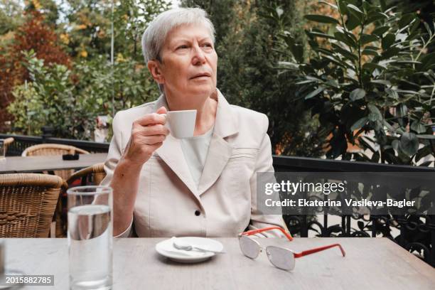 woman 60-69 years old drinks coffee in a cafe on the summer veranda - 60 69 years bildbanksfoton och bilder