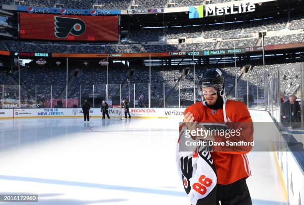 Joel Farabee of the Philadelphia Flyers takes of his game jersey after a team photo before practice at MetLife Stadium on February 16, 2024 in East...