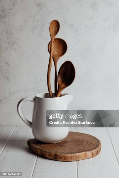 wooden spoons in a white milk jug on a wooden stand on a white background - cucchiaio di legno foto e immagini stock
