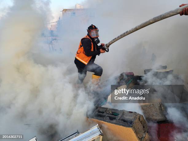 Civil defense teams and local residents try to extinguish a fire that broke out after a building hit by Israeli forces in Rafah, Gaza on February 19,...