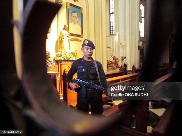 An Indonesia bomb-squad policeman stands guard as his fellow sweep inside the Jakarta's Katedral 24 December 2001 as part of security preparation...