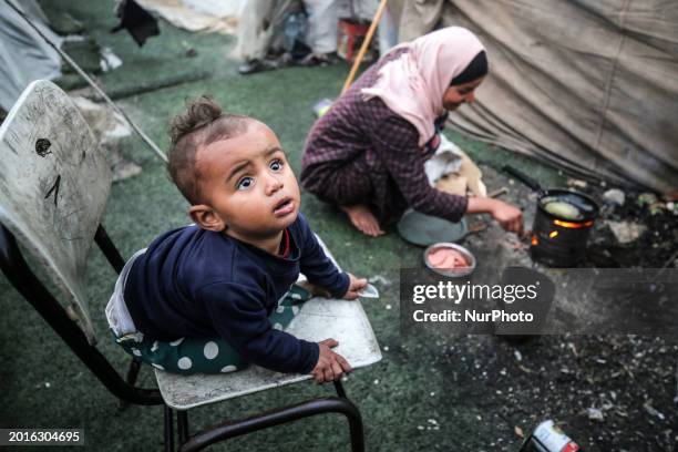 Palestinian children are seen near makeshift tents at a camp set up in Al-Durra Stadium in Deir Al-Balah in the central Gaza Strip, on February 19 as...