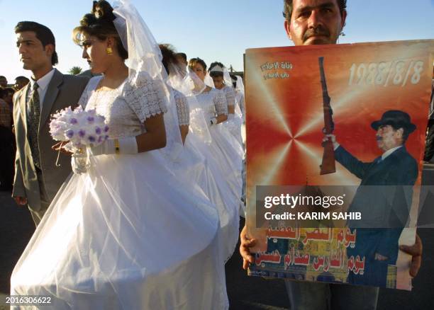An Iraqi man holds up a poster showing Iraqi President Saddam Hussein hold up a gun over Jerusalem's Dome of the Rock as Iraqi couples gather for a...