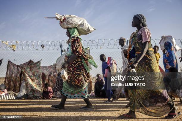 Sudanese refugees and South Sudanese returnees who have fled from the war in Sudan carry their belongings while arriving at a Transit Centre for...