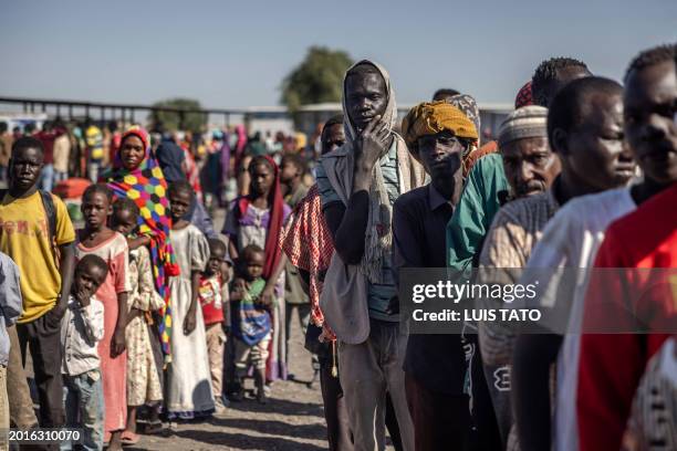 Sudanese refugees and ethnic South Sudanese families who have fled from the war in Sudan line up while waiting to board a truck to go to a Transit...