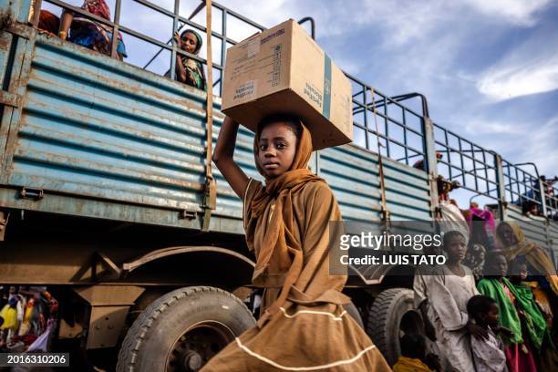 Sudanese girl who have fled from the war in Sudan with her family carry a box with some of her belongings after arriving at a Transit Centre for...