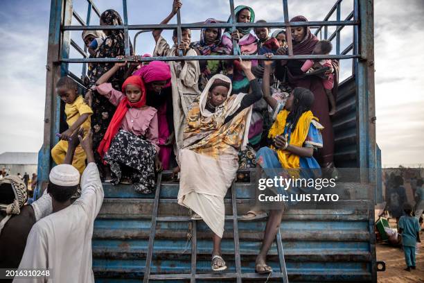 Sudanese refugees who have fled from the war in Sudan get off a truck loaded with families arriving at a Transit Centre for refugees in Renk, on...