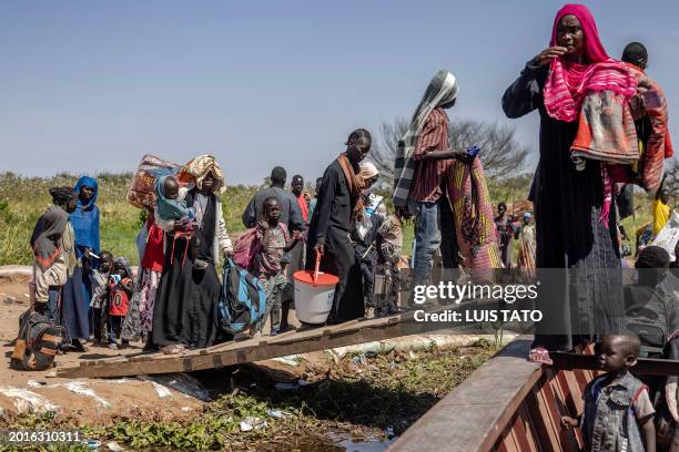 Sudanese refugees and ethnic South Sudanese who have fled the war in Sudan carry their belongings while boarding a boat at the shores of the White...