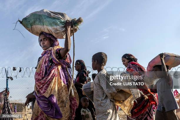 Sudanese families who have fled from the war in Sudan carry their belongings while arriving at a Transit Centre for refugees in Renk, on February 14,...