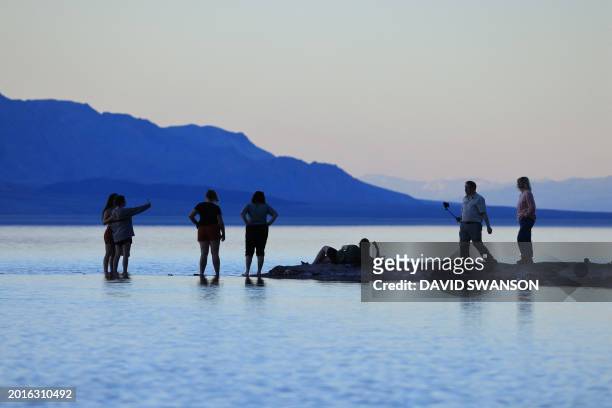 Tourists enjoy the rare opportunity to walk in water as they visit Badwater Basin, the normally driest place in the US, in Death Valley National...