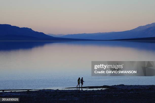 Tourists enjoy the rare opportunity to walk in water as they visit Badwater Basin, the normally driest place in the US, in Death Valley National...