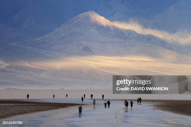 Tourists enjoy the rare opportunity to walk in water as they visit Badwater Basin, the normally driest place in the US, in Death Valley National...