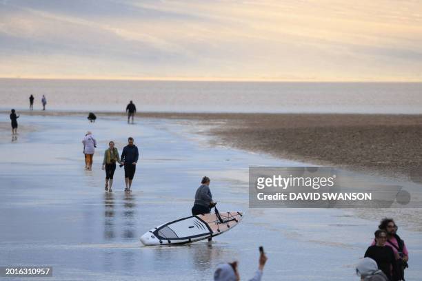 Person drags a paddle board as tourists enjoy the rare opportunity to walk in water as they visit Badwater Basin, the normally driest place in the...