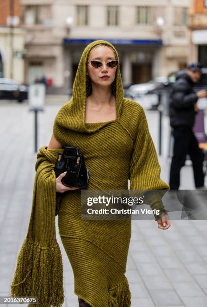 Betty Bachz wears hooded knit dress, brown boots, black bag outside Mark Fast during London Fashion Week February 2024 on February 16, 2024 in...