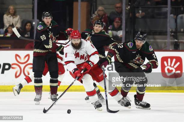 Brent Burns of the Carolina Hurricanes skates with the puck under pressure from Jack McBain of the Arizona Coyotes during the second period of the...