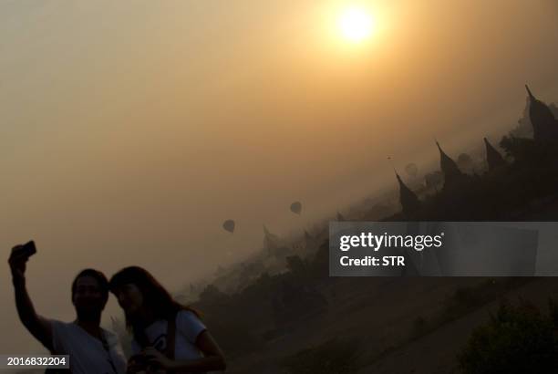 Couple take a photo of themselves as the sun rises above the pagodas in Myanmar's northern ancient town of Bagan on February 26, 2012. AFP PHOTO
