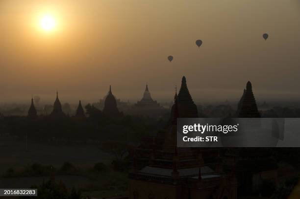 Hot air balloons carrying tourists fly above the pagodas as the sun rises in Myanmar's northern ancient town of Bagan on February 26, 2012. AFP PHOTO