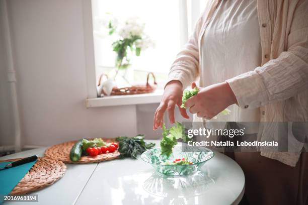 curvy teenager ripping lettuce leaves for fresh veggie salad at home. - curvy girls imagens e fotografias de stock