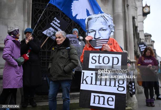 Demonstrators hold placards as they protest outside of the Royal Courts of Justice, Britain's High Court, in central London on February 20 as the...
