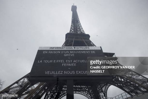 This photograph shows a board informing visitors that the Eiffel Tower, viewed in the background, is closed, during a strike of the Eiffel Tower's...