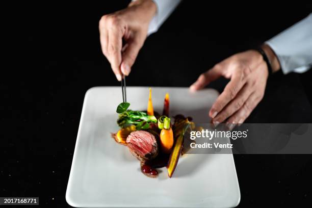 el chef está terminando la preparación del plato - plato de carne fotografías e imágenes de stock