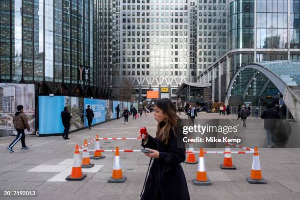 Cordoned off area of red and white cones to prevent pedestrians from tripping on broken paving stones at the heart of Canary Wharf financial district...