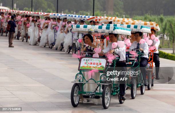 Group wedding couples rides cycle carts as part of a mass wedding ceremony at a park in Wuhan, in central China's Hubei province on May 1, 2011. The...