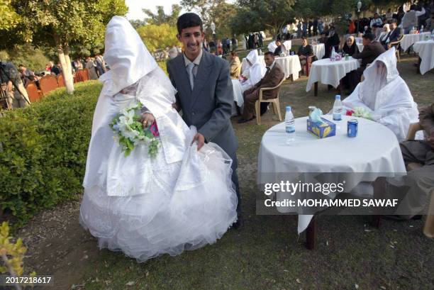 Bride and groom stand together during a mass wedding ceremony in the grounds of ancient Babylon some 100 kms south of Baghdad on December 01, 2008....