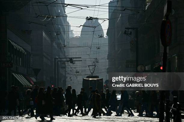 People cross a busy street in Milan's city center on February 20, 2024. Gas-guzzling cars were banned from roads Tuesday in Milan and eight other...