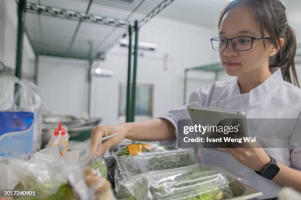 asian female apprentice kitchen checking cooking ingredient - restaurant kitchen fridge stock pictures, royalty-free photos & images