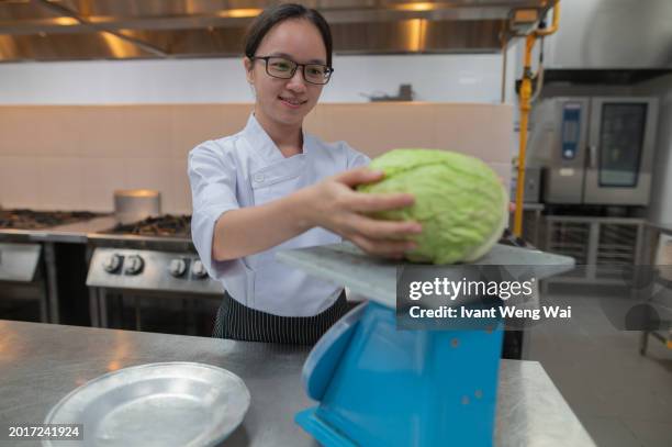 asian female apprentice kitchen using scale for vegetable - mass timber stock pictures, royalty-free photos & images