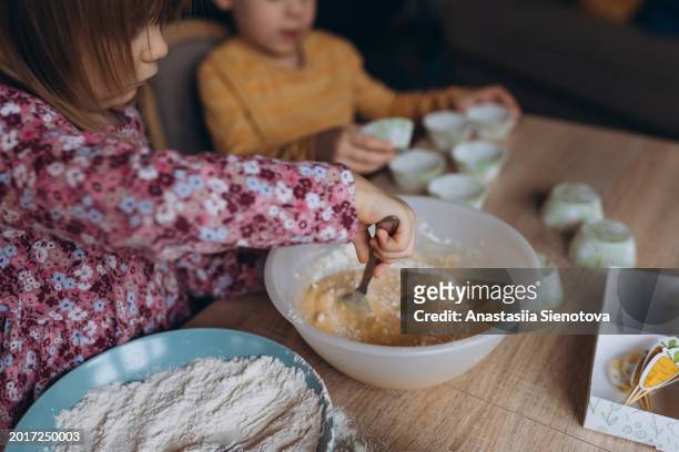 boy and girl preparing muffin dough at home - cupcake holder stock pictures, royalty-free photos & images
