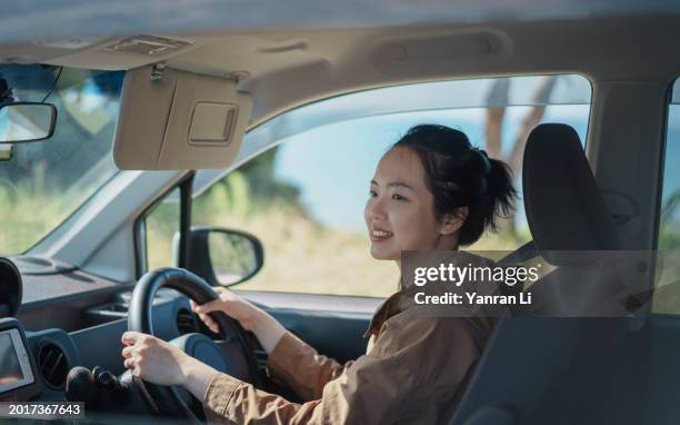 young asian woman driving happily on sunny day - right hand drive stock pictures, royalty-free photos & images