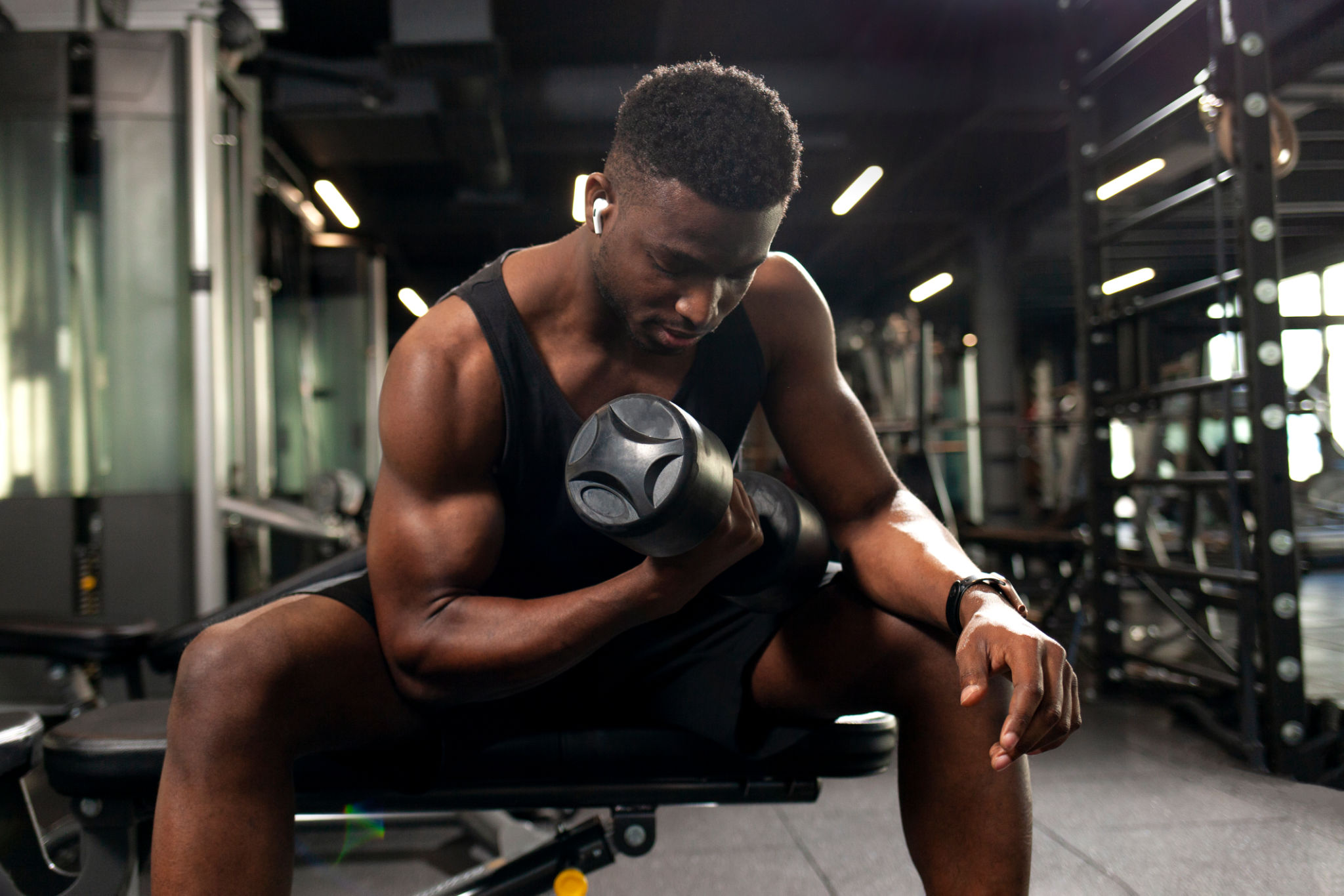 athletic african american man trains in dark gym, athletic guy lifts heavy dumbbells in fitness club athletic african american man trains in dark gym, athletic guy lifts heavy dumbbells in fitness club