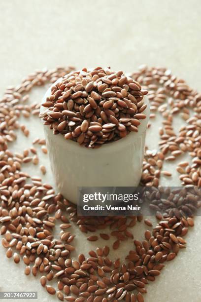 close-up of flax seeds in a white ceramic bowl against white background/still life - omega 3 stock pictures, royalty-free photos & images