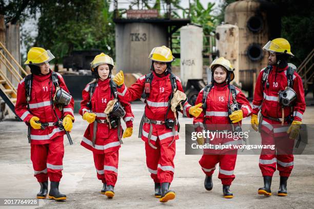 teamwork of firefighters undergoing advanced fire suppression training by simulating fire control in industrial plants with gas pipelines or oil pipelines. - roupa a prova de fogo - fotografias e filmes do acervo