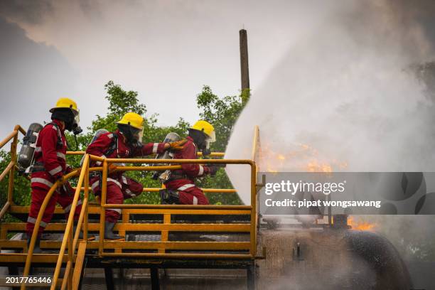 teamwork of firefighters undergoing advanced fire suppression training by simulating fire control in industrial plants with gas pipelines or oil pipelines. - fire service stock pictures, royalty-free photos & images