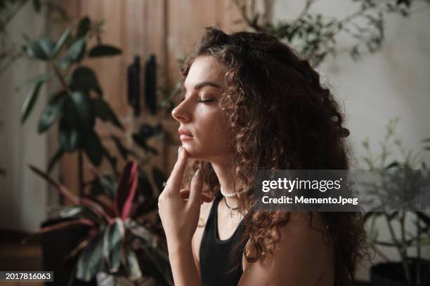 calm peaceful woman touching chin with fingertips, keeping eyes closed, practicing eft tapping to relieve stress, anxiety or pain. emotional freedom technique - tap forehead stock pictures, royalty-free photos & images