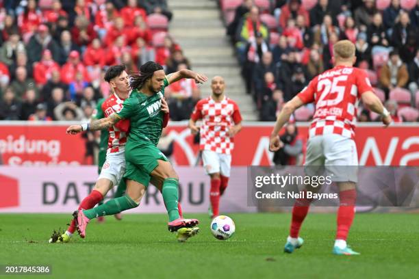 Kevin Mbabu of FC Augsburg is challenged by Anthony Caci of 1.FSV Mainz 05 during the Bundesliga match between 1. FSV Mainz 05 and FC Augsburg at...