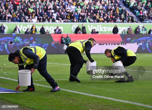 Stewards collect small items thrown onto the pitch by fans in protest of the DFL's investment plans prior to the Bundesliga match between VfL...