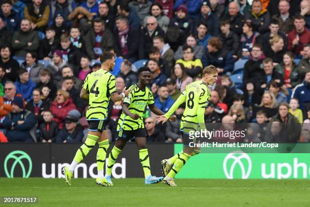 Martin Odegaard of Arsenal celebrates with teammates Ben White and Bukayo Saka after scoring his team's first goal during the Premier League match...